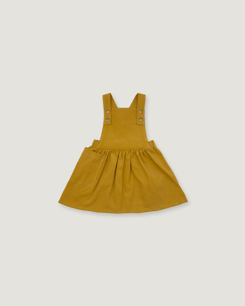 A mustard yellow toddler pinafore dress with adjustable shoulder straps and decorative metal buttons, shown flat on a light gray background.