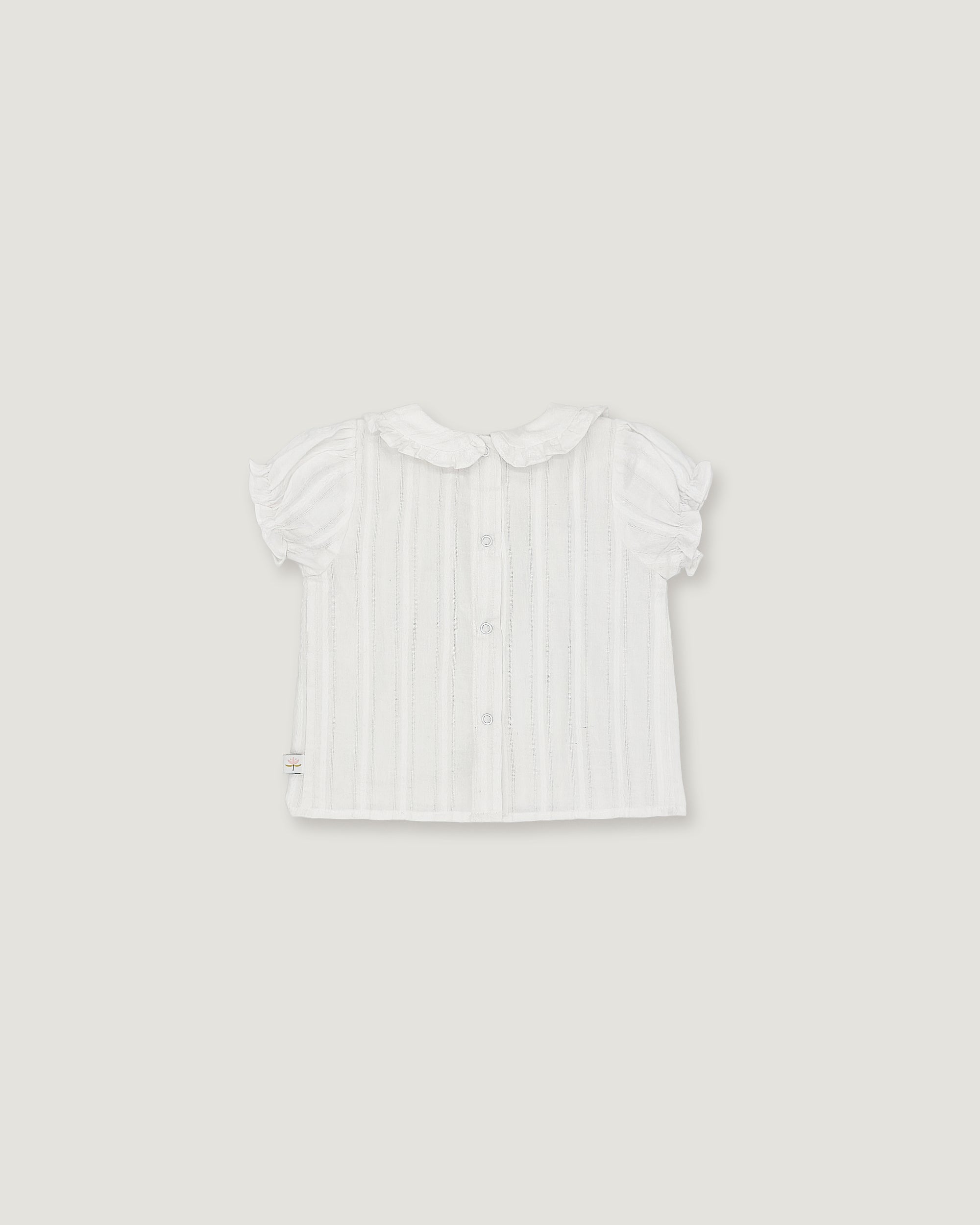 A white short-sleeve baby top with vertical ruffles, a Peter Pan collar, and a button-up front, shown flat against a light gray background.