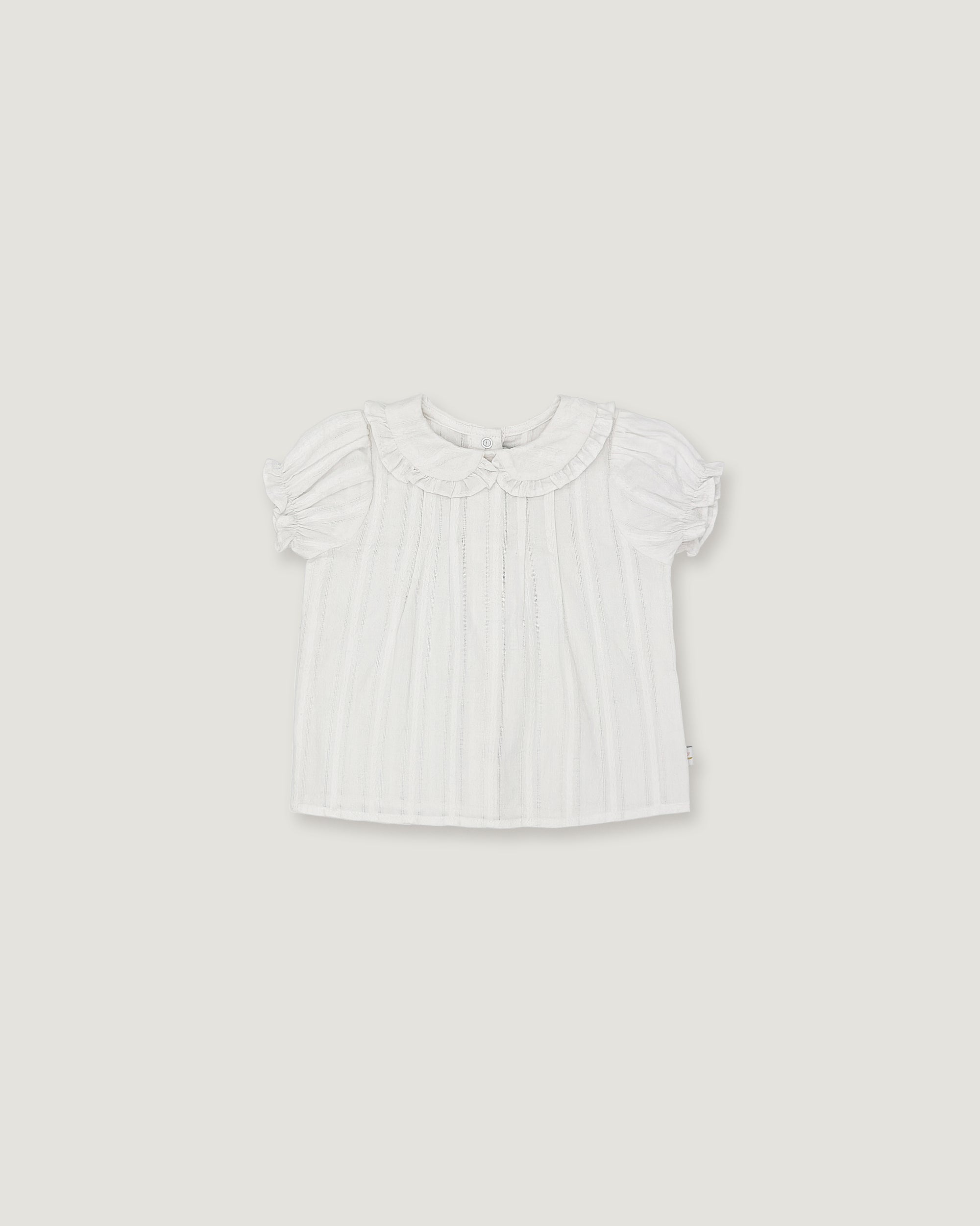 A white short-sleeve baby top with a ruffled Peter Pan collar and subtle vertical pleats, shown flat against a light gray background.