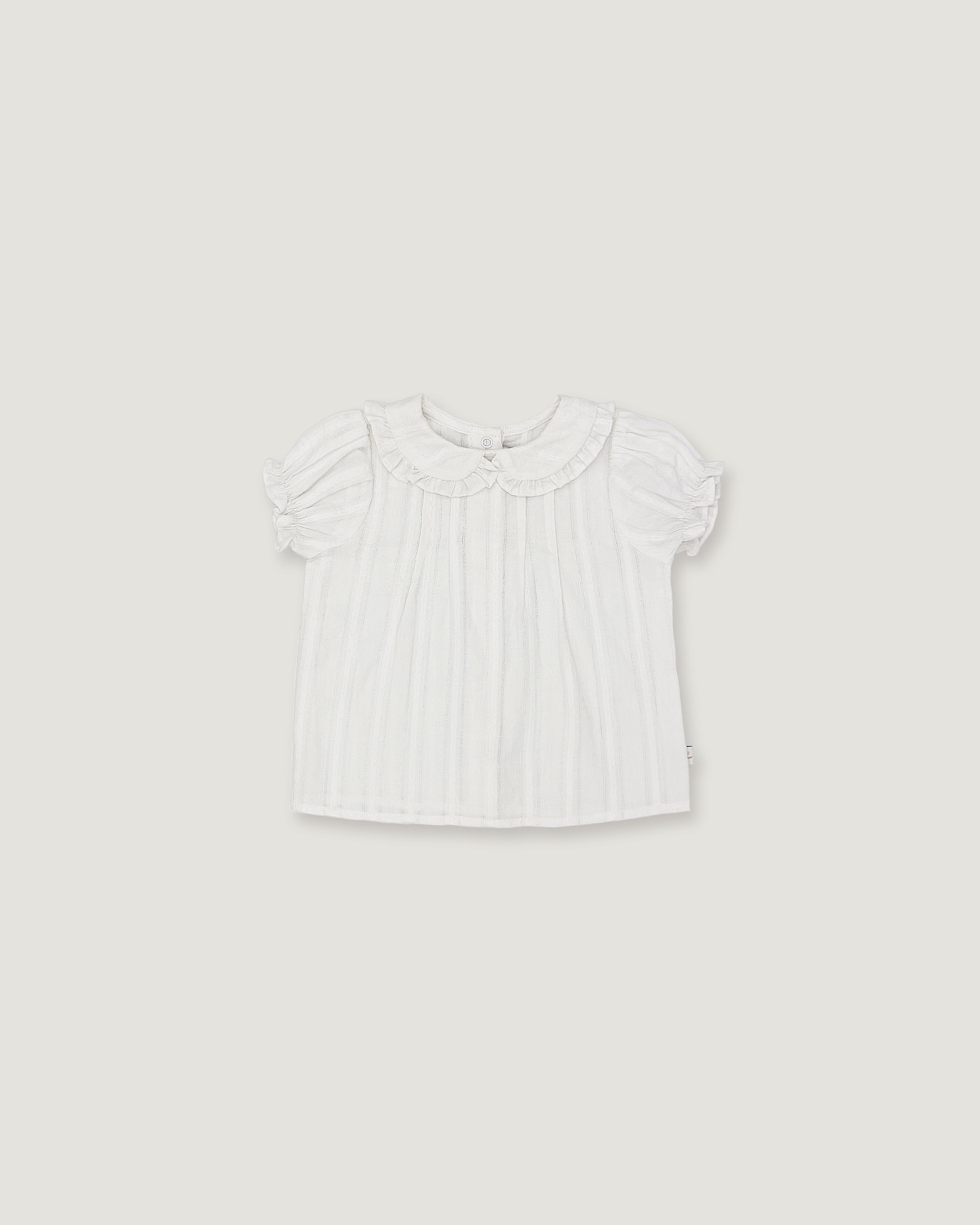 A white short-sleeve baby top with a ruffled Peter Pan collar and subtle vertical pleats, shown flat against a light gray background.