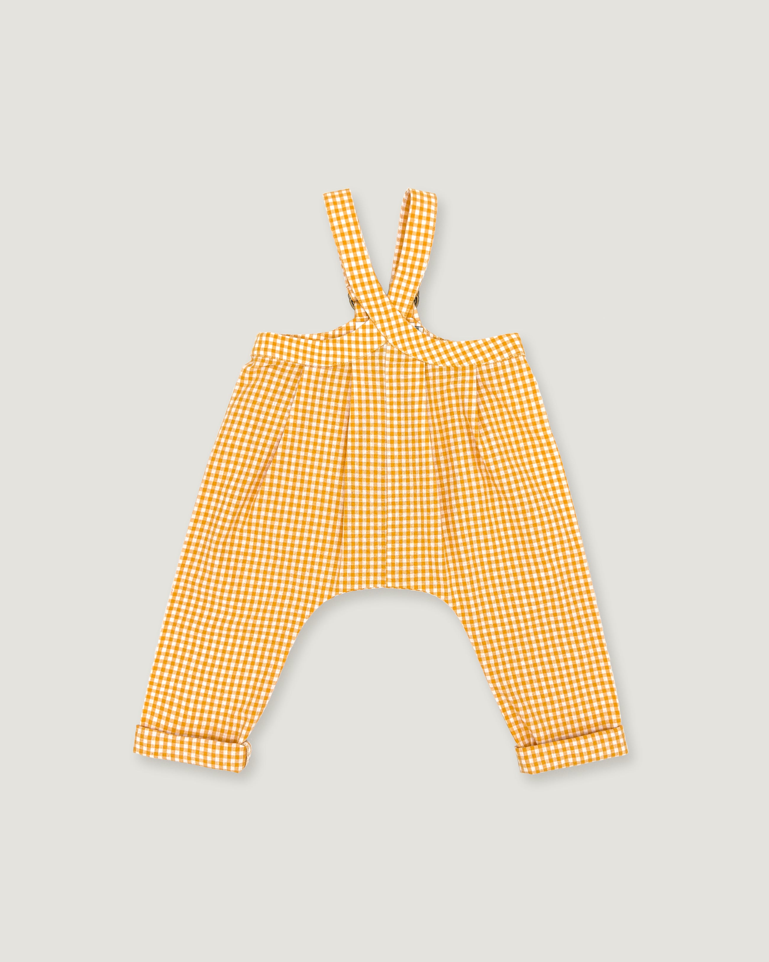 A pair of yellow and white gingham baby pants with shoulder straps, laid flat on a light gray background.