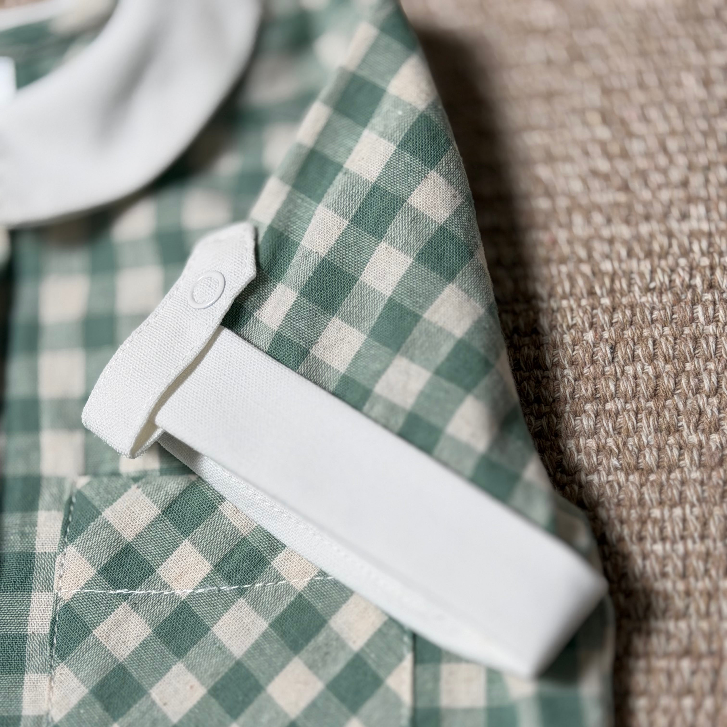 Green and white checkered shirt with a white collar on a textured surface