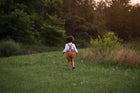 Model boy wearing the Burnt Orange Suspender Shorts with Beige Gingham Henley Shirt, back view - This image showcases the back of the outfit, highlighting the adjustable straps and how they complement the overall look.