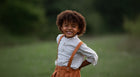 Beige Gingham Henley Shirt worn by a laughing 5-year-old boy in size 5Y, featuring a classic Henley placket and 3/4 cuffed sleeves that can be unrolled for layering. Paired with burnt orange linen suspender shorts for a stylish, versatile outfit.