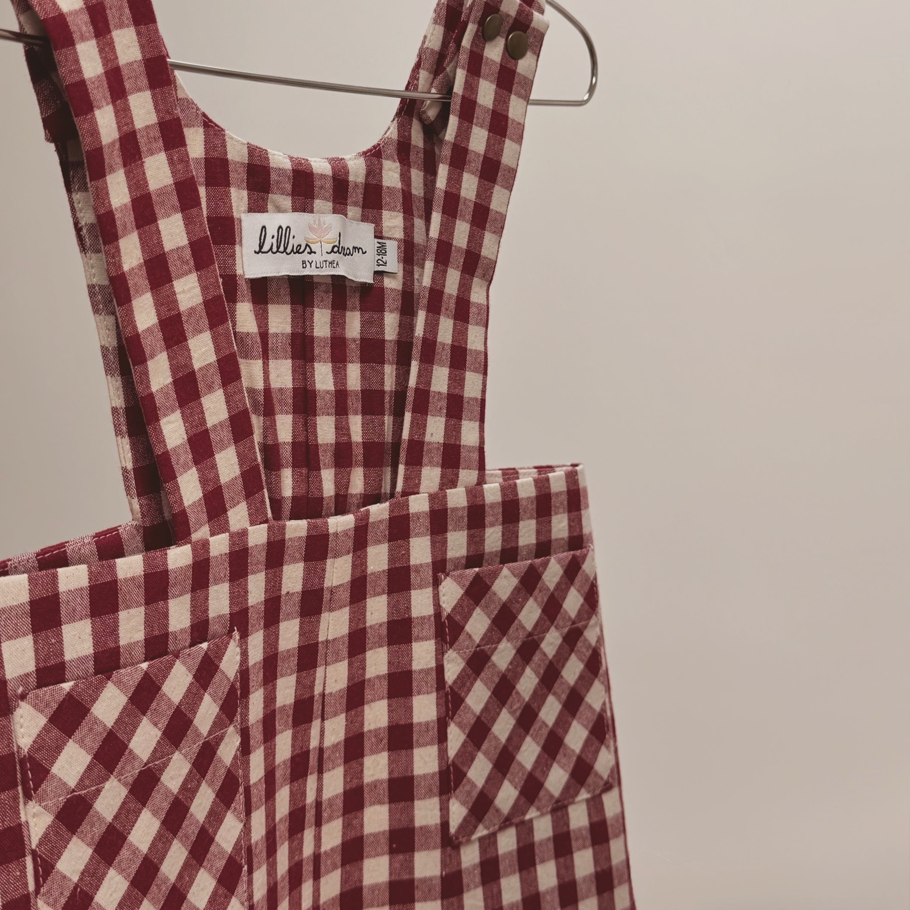Red and white checkered dress with a brand label on a hanger against a plain background