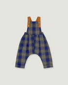 A baby romper with blue, beige, and white plaid patterned fabric, featuring tan shoulder straps with snap buttons, shown flat on a light gray background.