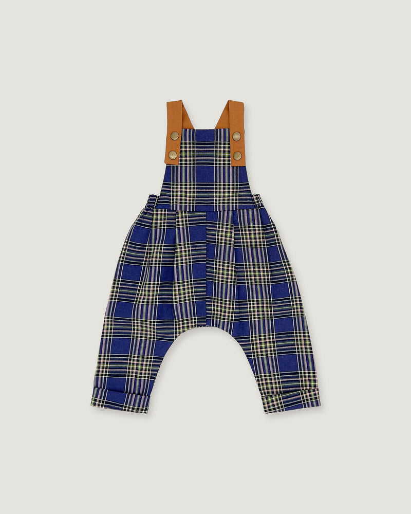 A baby romper with blue, beige, and white plaid patterned fabric, featuring tan shoulder straps with snap buttons, shown flat on a light gray background.