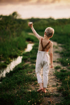 Child walking along a path by a river with a sunset in the background