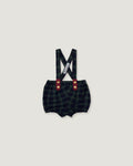 A pair of baby boy's plaid bib shorts with suspenders, featuring a dark green and black checkered pattern, red button accents, and a white brand tag on the suspenders, shown against a solid light gray background.