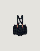 A pair of baby boy's plaid bib shorts with suspenders, featuring a dark green and black checkered pattern, red button accents, and a white brand tag on the suspenders, shown against a solid light gray background.