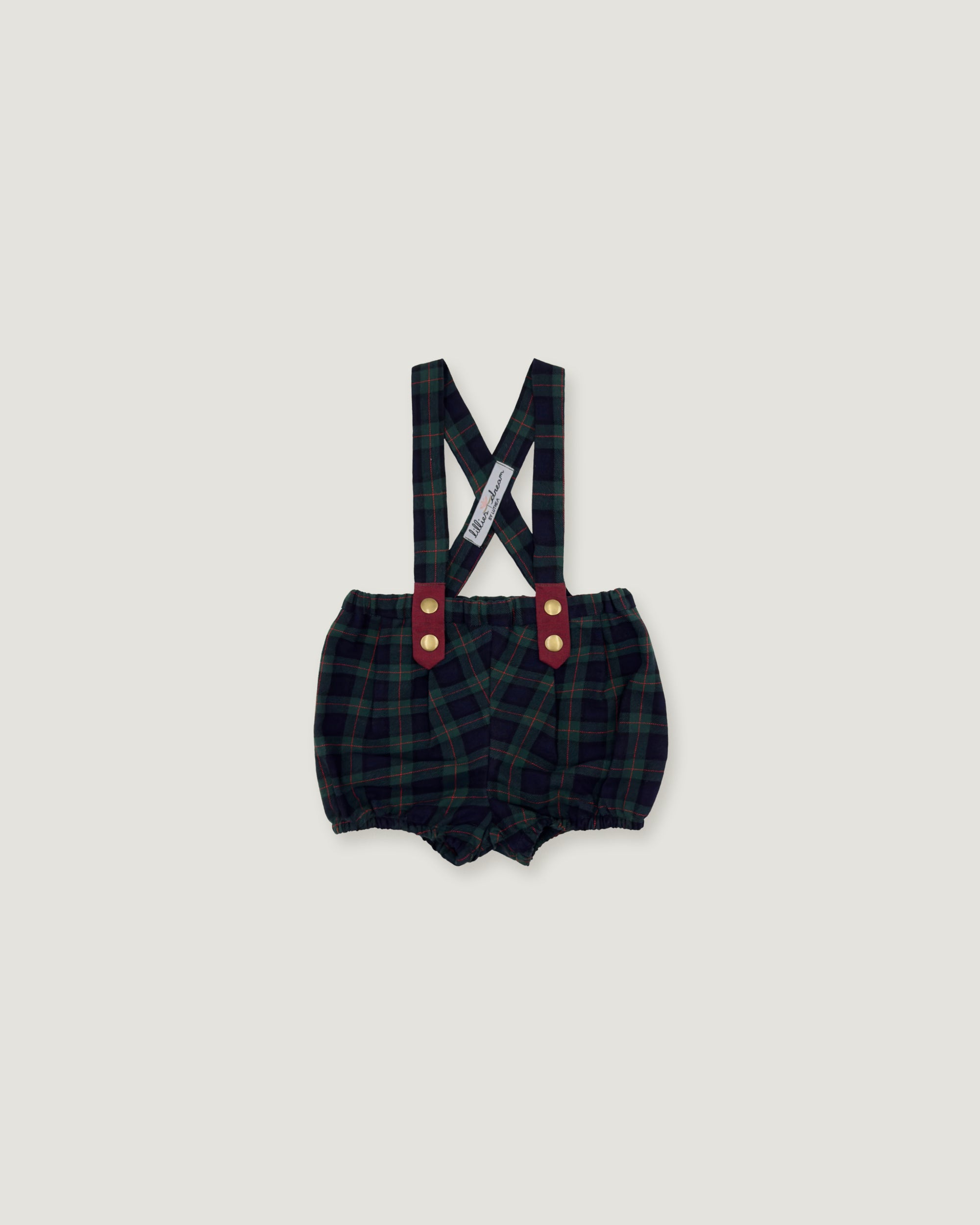 A pair of baby boy's plaid bib shorts with suspenders, featuring a dark green and black checkered pattern, red button accents, and a white brand tag on the suspenders, shown against a solid light gray background.