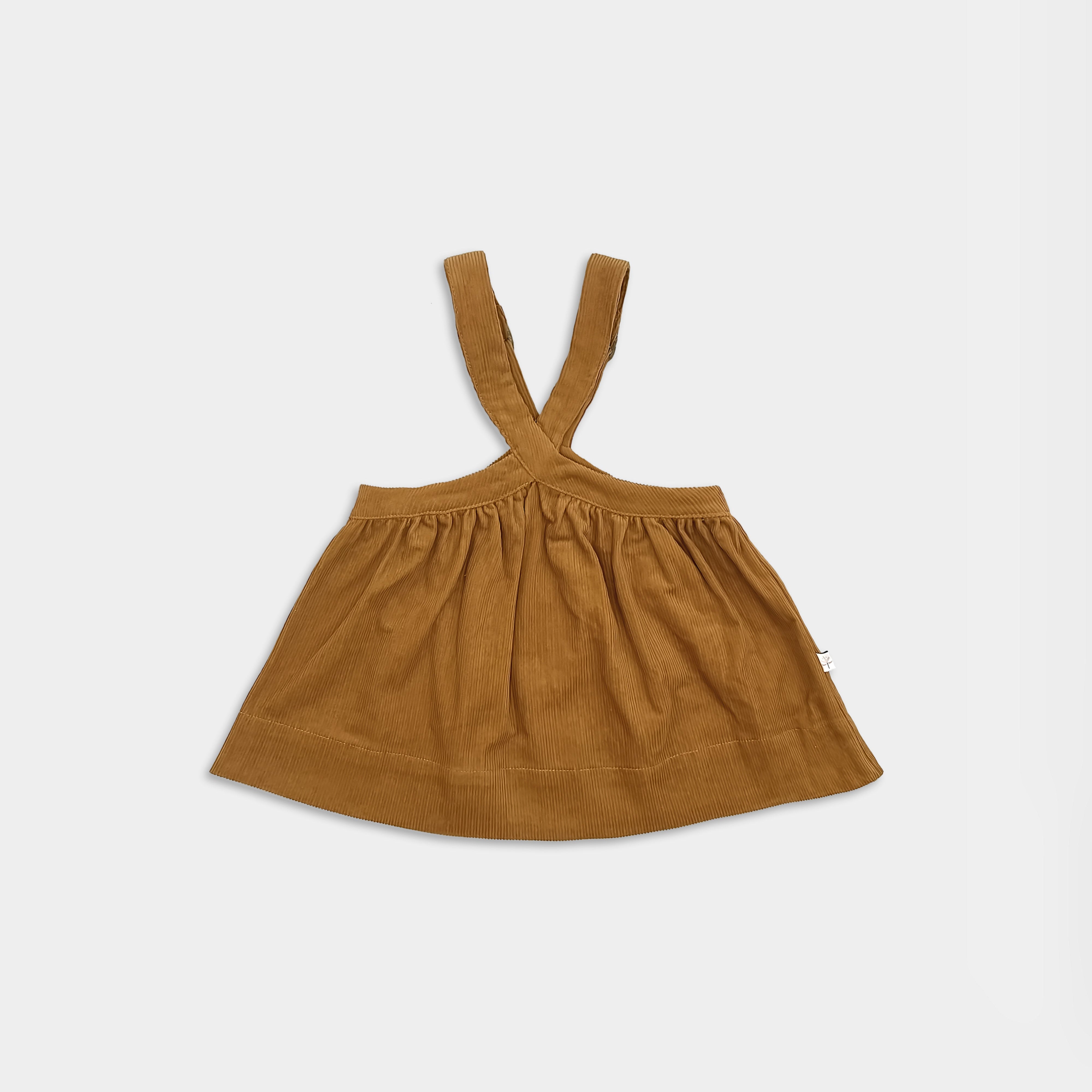Front view of pinafore for small girls with suspenders on a light grey background