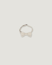 A light cream-colored bow tie with a textured fabric bow and a thin band, shown against a solid light gray background.