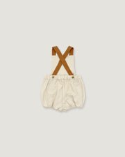 A baby romper with cream-colored fabric and brown suspenders, shown flat on a light gray background.