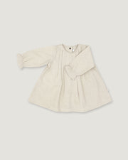 A light beige linen long-sleeve dress for toddlers, featuring a gathered waist with a bow detail, pleated front, and elasticized cuffs, shown on a neutral light gray background.