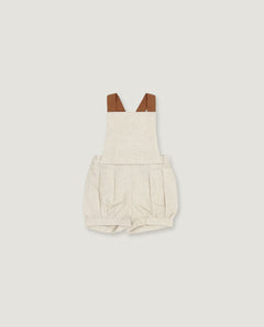 A baby romper in a light oatmeal-beige linen-like fabric, featuring brown faux-leather shoulder straps, shown flat on a light gray background.