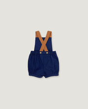 A pair of navy blue baby bloomers with tan suspenders, laid flat against a light gray background.