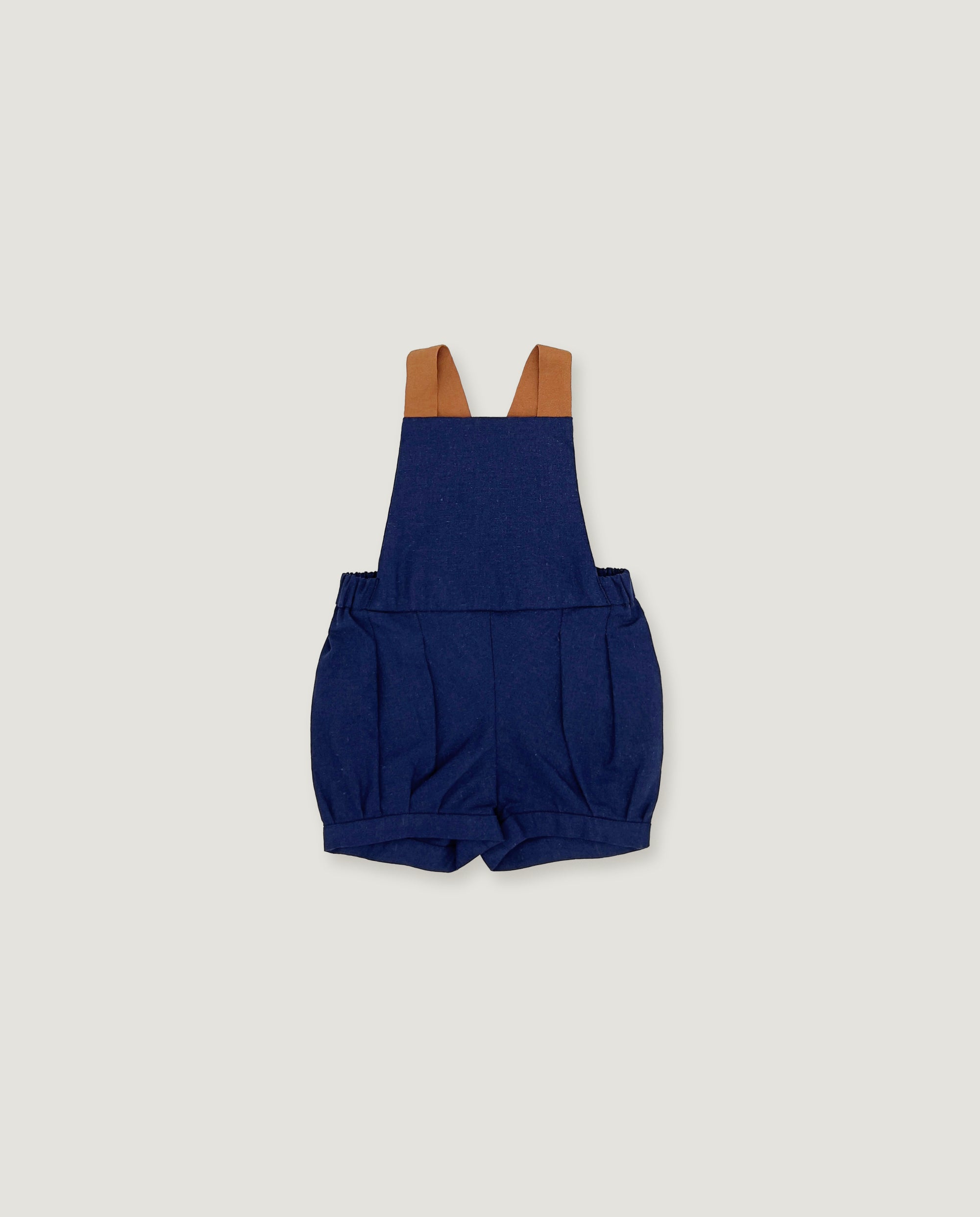 A pair of navy blue baby shorts with adjustable brown shoulder straps, laid flat against a light gray background.