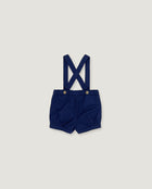 A pair of navy blue baby boy shorts with adjustable shoulder straps and metal snap buttons, laid flat on a light gray background.