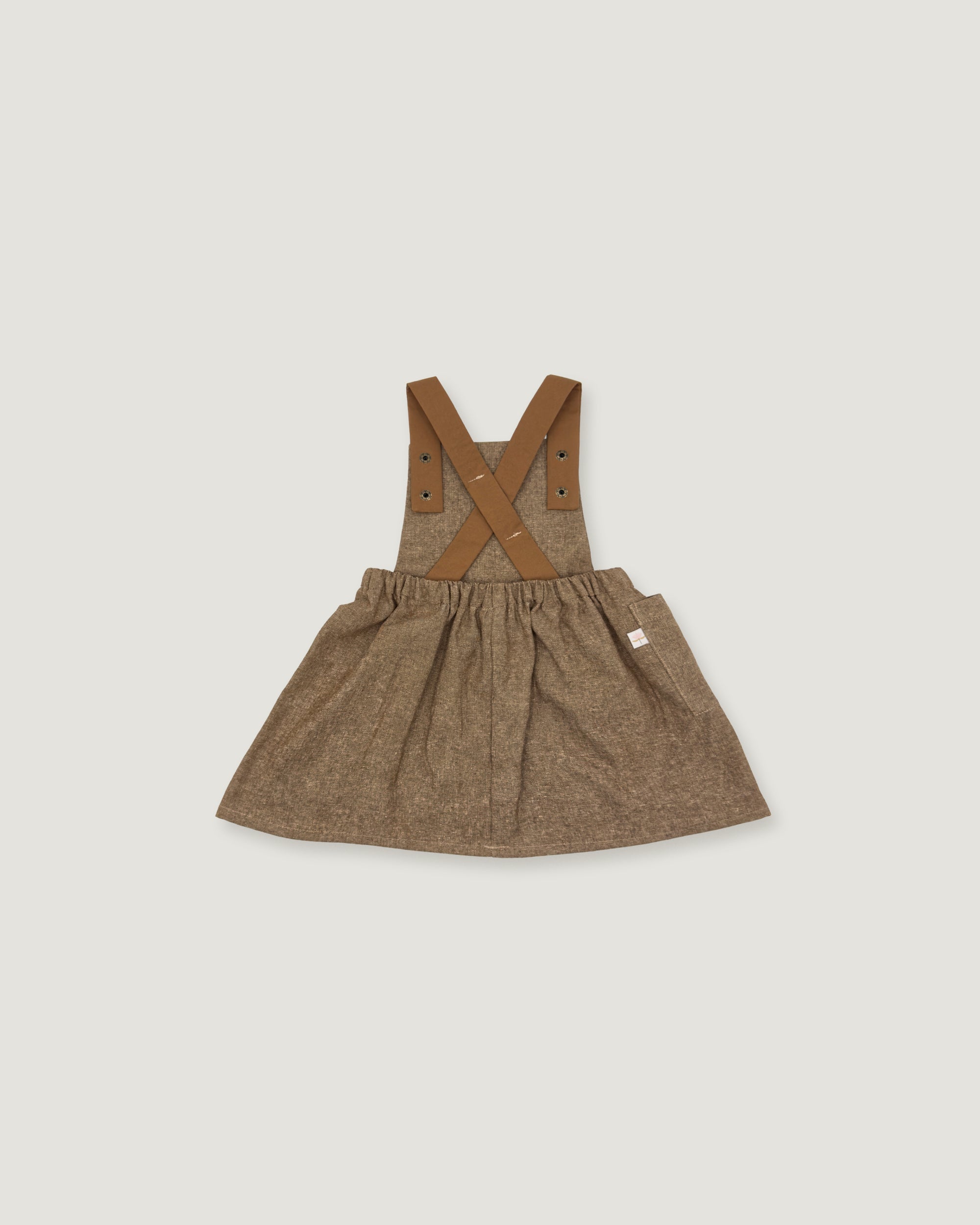 A toddler girl's brown textured linen overall dress with adjustable shoulder straps and a gathered skirt, shown flat on a light gray background.
