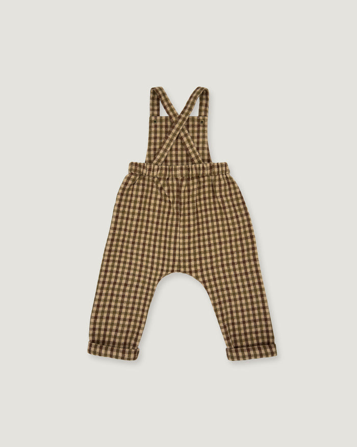 A baby romper with suspenders in a brown and beige gingham check pattern, laid flat on a light gray background.