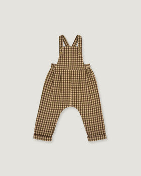 A baby romper with brown and beige gingham check print, featuring shoulder straps and a wide leg design, shown flat on a light gray background.