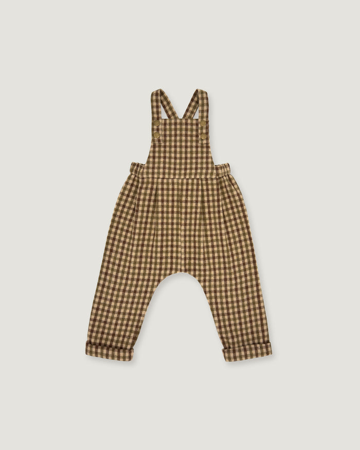 A baby romper with brown and beige gingham check print, featuring shoulder straps and a wide leg design, shown flat on a light gray background.