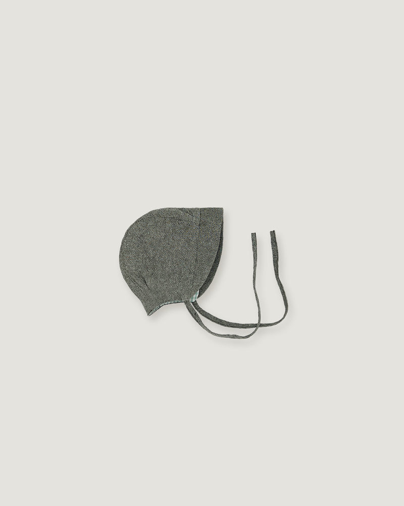 A green gray fabric bonnet with long ties, photographed flat against a solid light gray background.