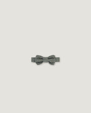 A small gray bow tie with a textured, glittery finish, centered on a solid light gray background.