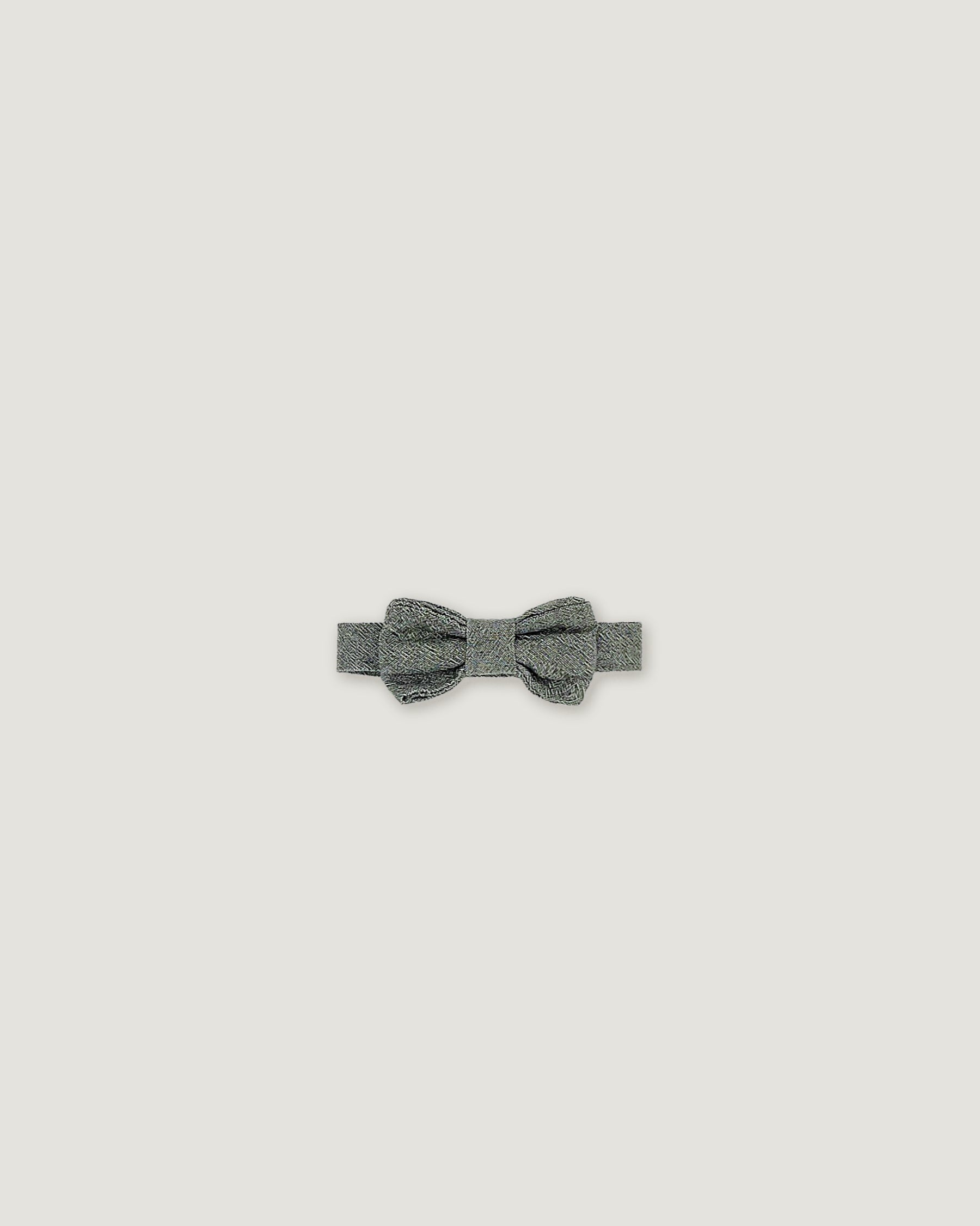 A small gray bow tie with a textured, glittery finish, centered on a solid light gray background.