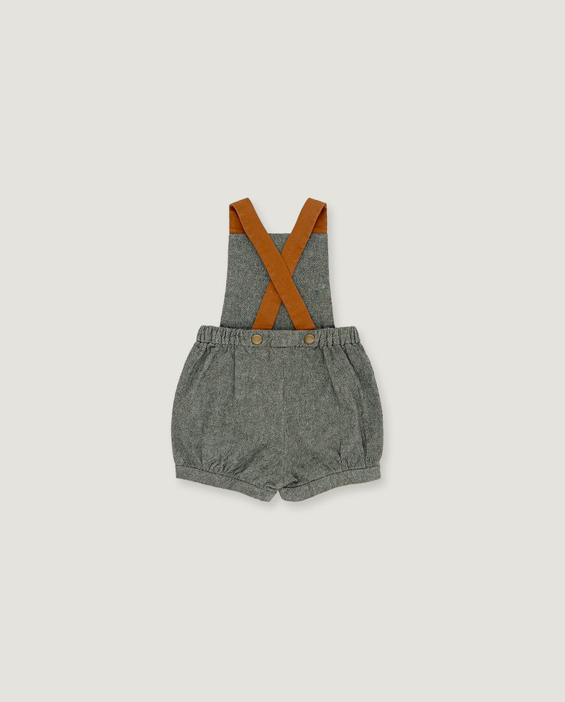 A baby romper with gray textured fabric shorts and brown suspenders, laid flat against a light gray background.