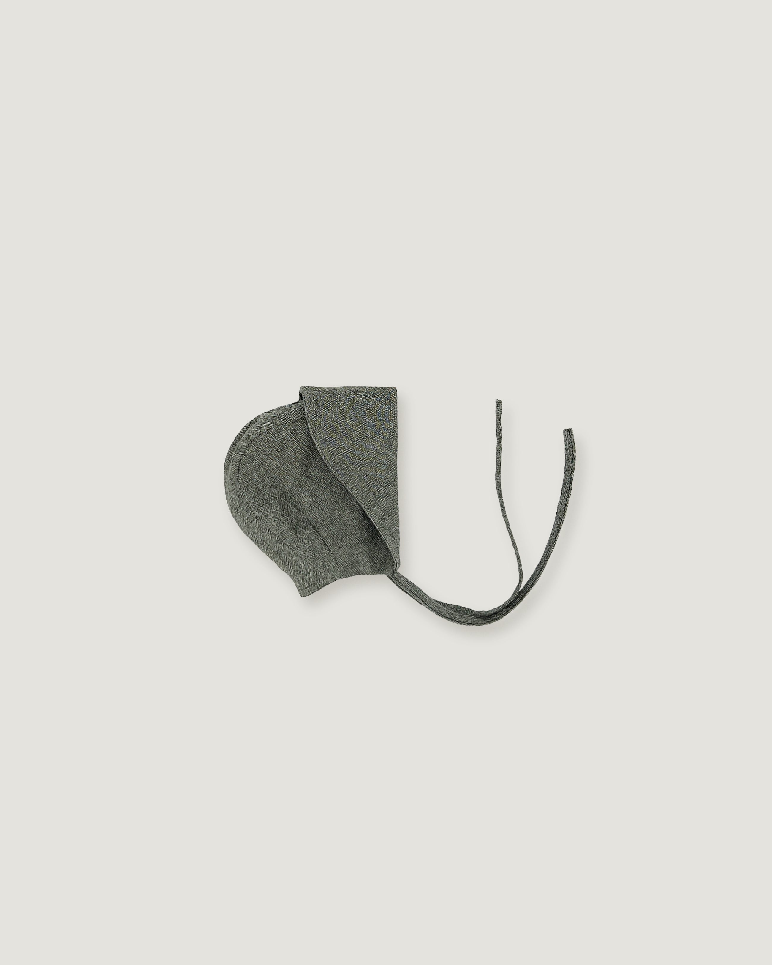 A green linen bonnet with a long visor rolled up  on a white background
