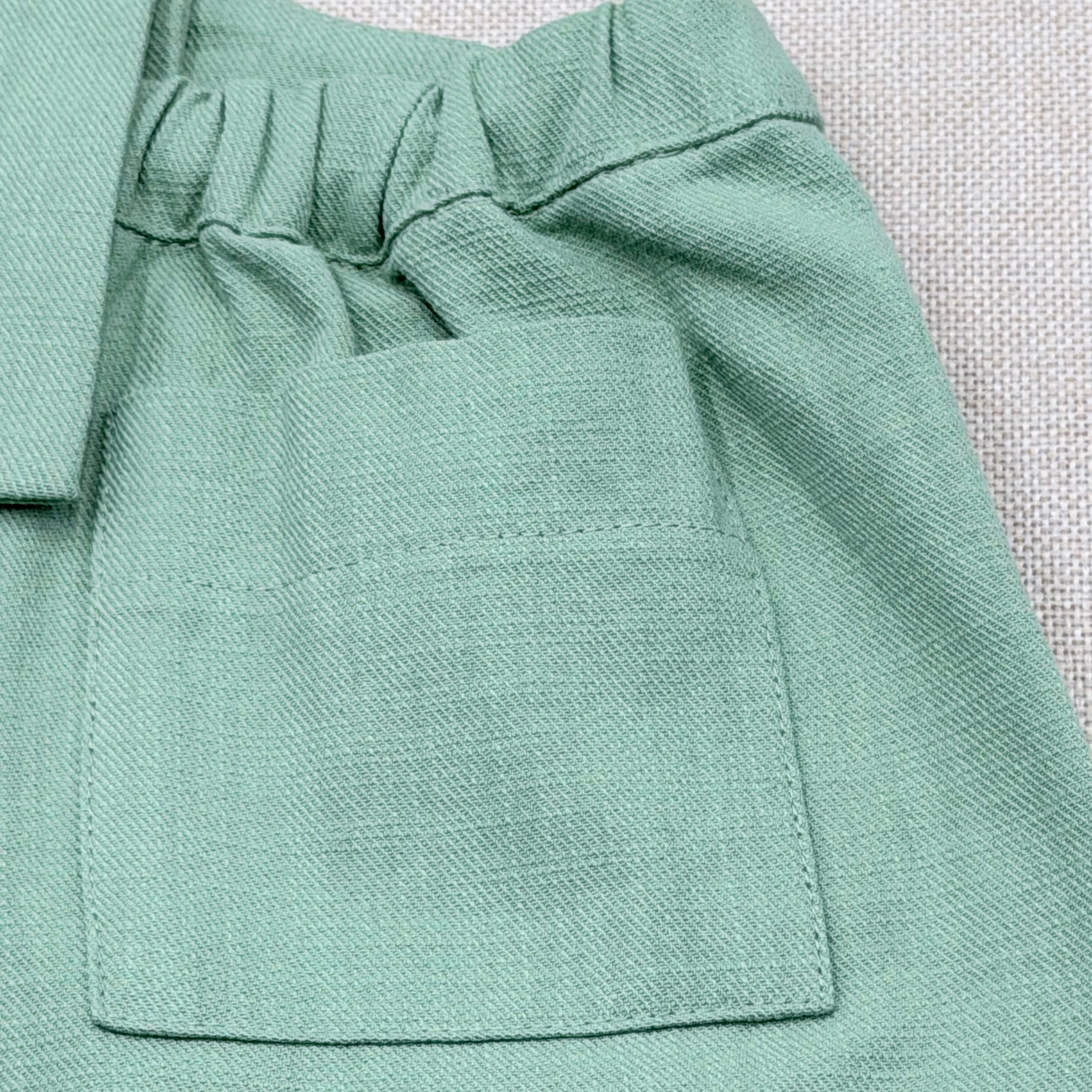 Close-up of a light green fabric with a pocket on a textured background