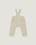A pair of baby trousers in a light cream or beige color, featuring a bib-style waistband with adjustable shoulder straps and cuffed legs, shown flat against a light gray background.