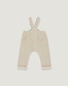 A pair of baby trousers in a light cream or beige color, featuring a bib-style waistband with adjustable shoulder straps and cuffed legs, shown flat against a light gray background.