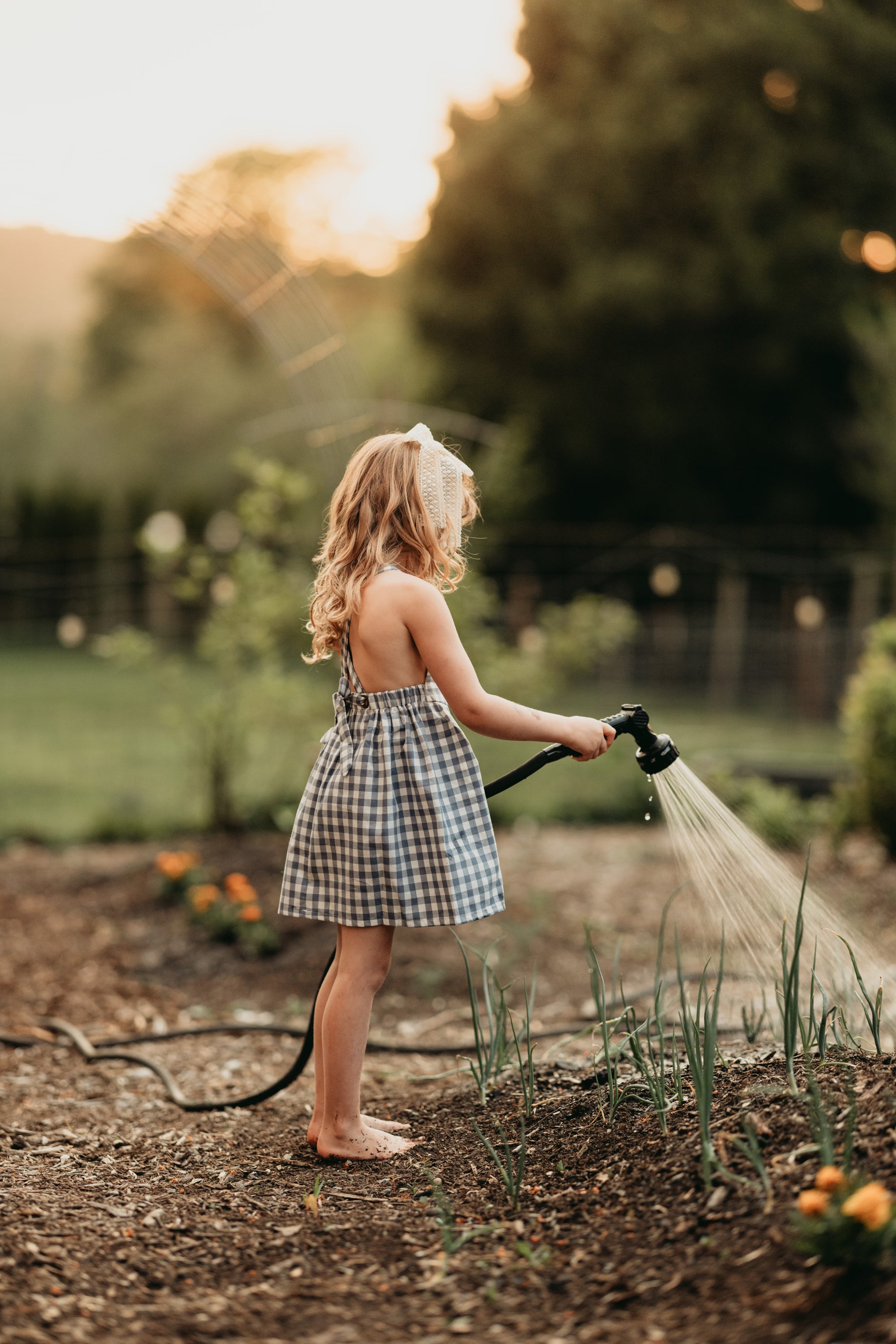Side view of the model wearing a similar pinafore: A 5-year-old girl wearing a similar style pinafore in Slate Gingham, demonstrating the garment’s side profile and fit.