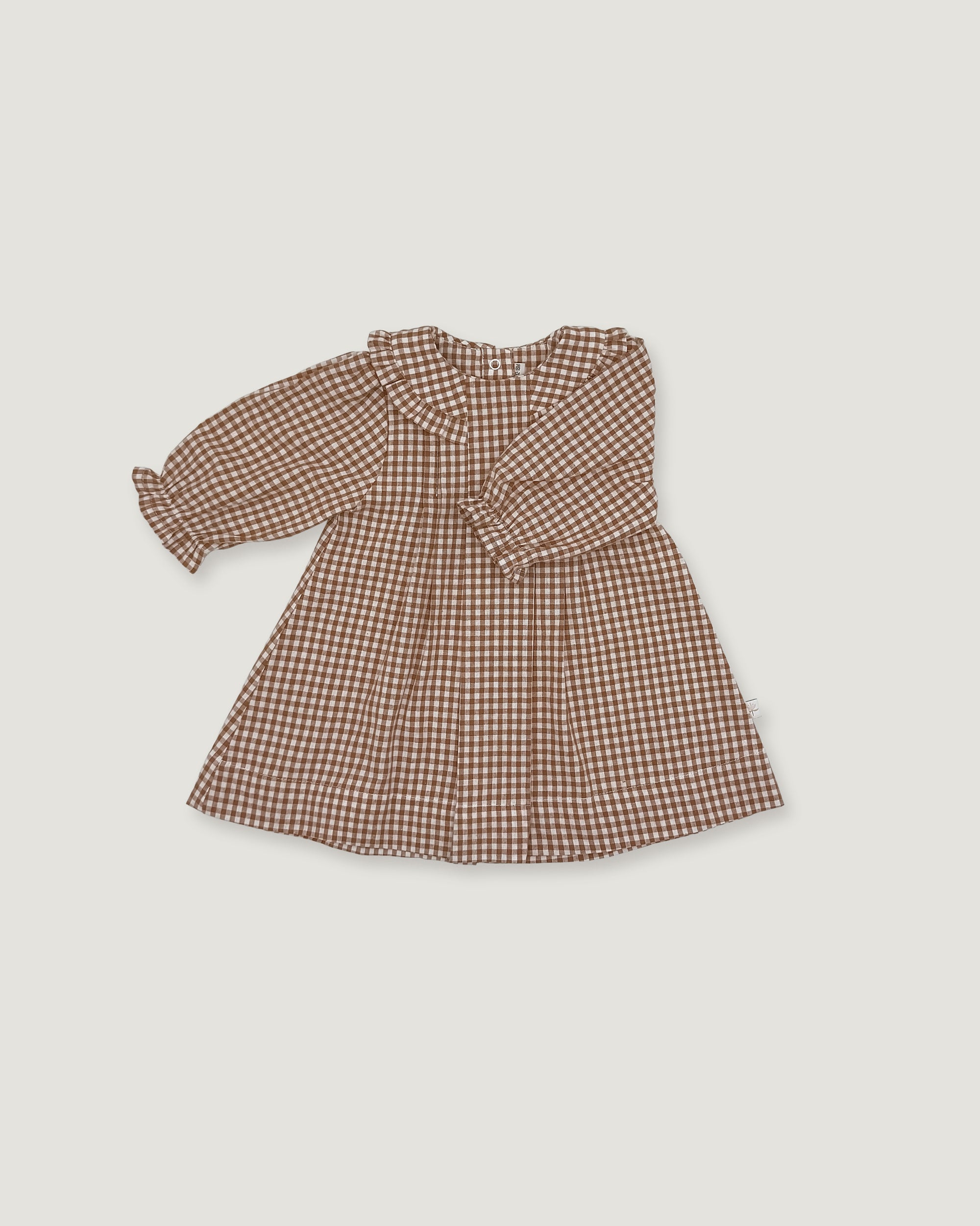 A long-sleeve baby dress with a brown and beige gingham pattern, featuring a ruffled collar and a gathered waist, shown flat on a light gray background.
