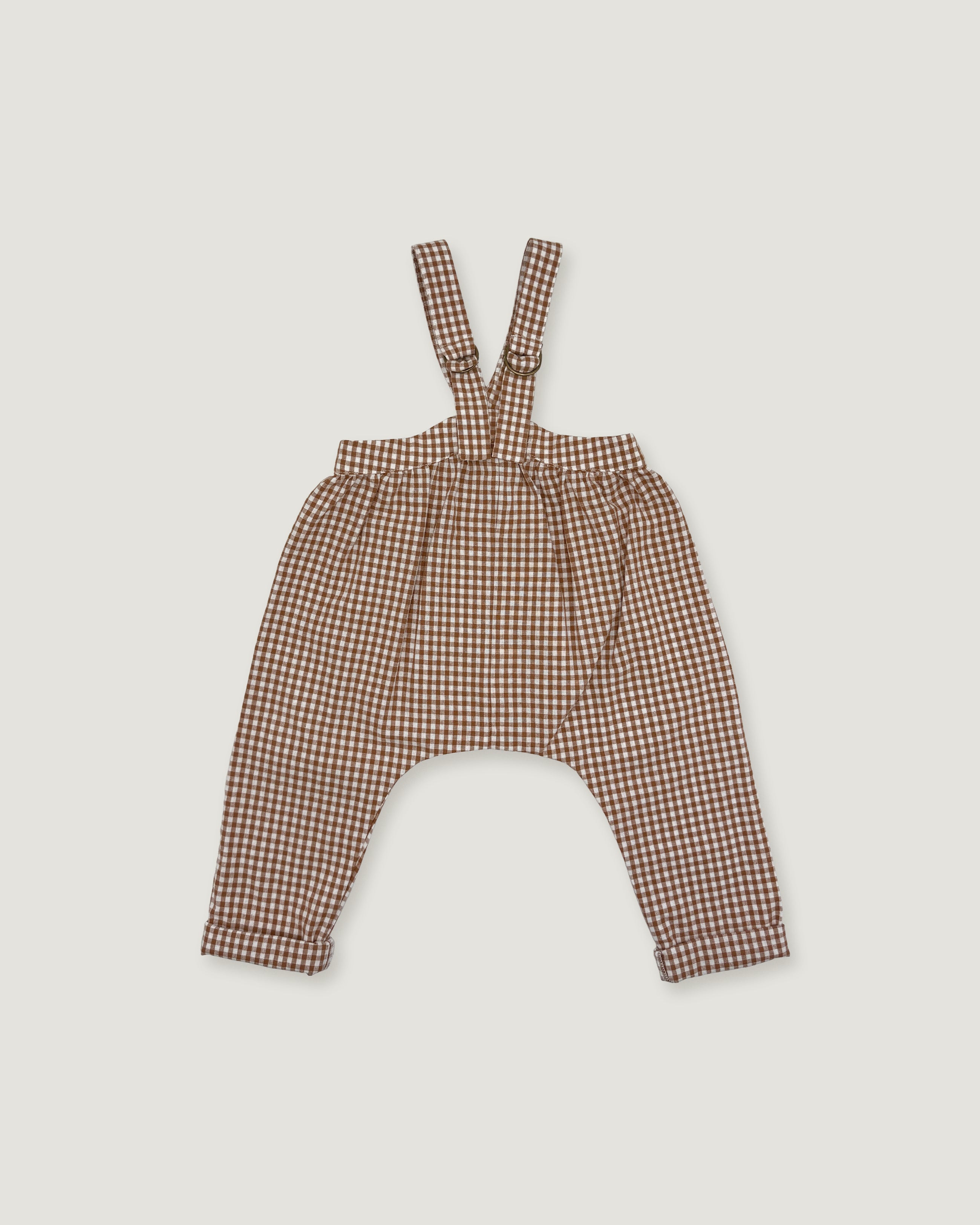 Brown and beige gingham patterned baby overalls with shoulder straps, laid flat on a light gray background.