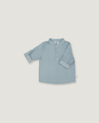A light blue long-sleeve shirt for toddlers, featuring a polo-style collar and a short button placket, laid flat against a neutral light gray background.