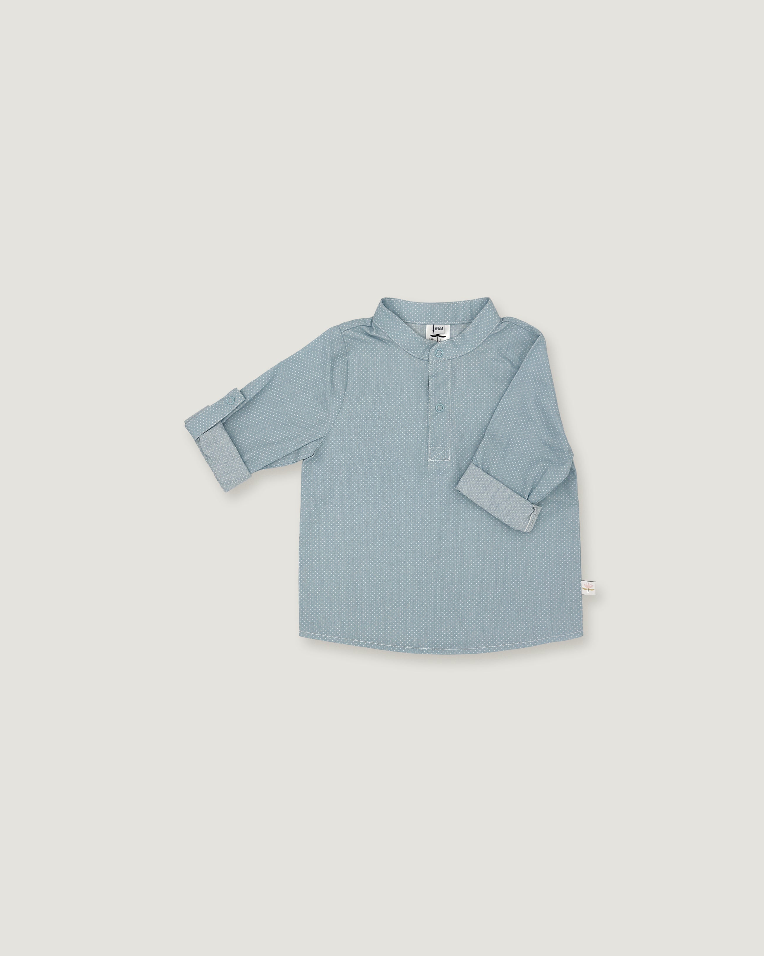 A light blue long-sleeve shirt for toddlers, featuring a polo-style collar and a short button placket, laid flat against a neutral light gray background.