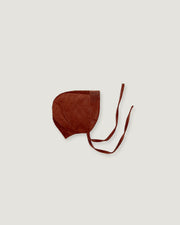A dark brown corduroy bonnet with long tie straps, laid flat on a light gray background.