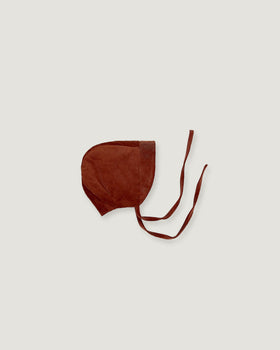 A dark brown corduroy bonnet with long tie straps, laid flat on a light gray background.