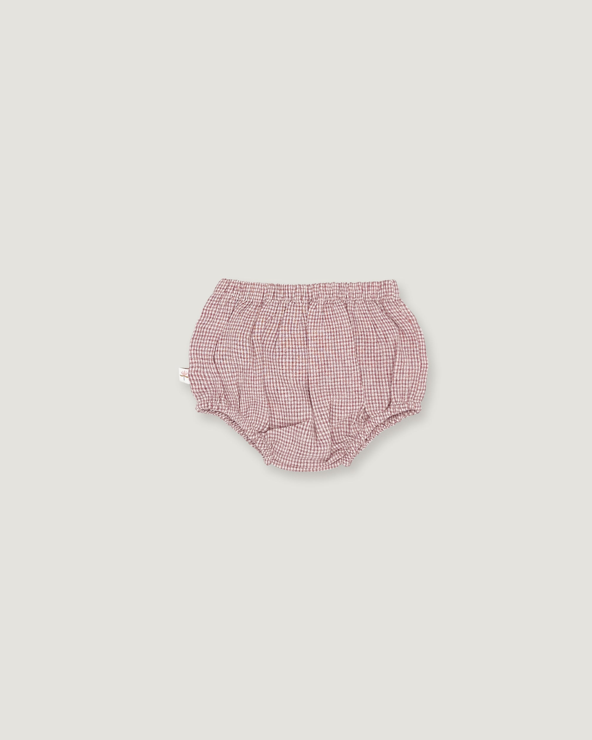 A pair of baby bloomers in a pink and white gingham pattern, photographed flat against a solid light gray background.