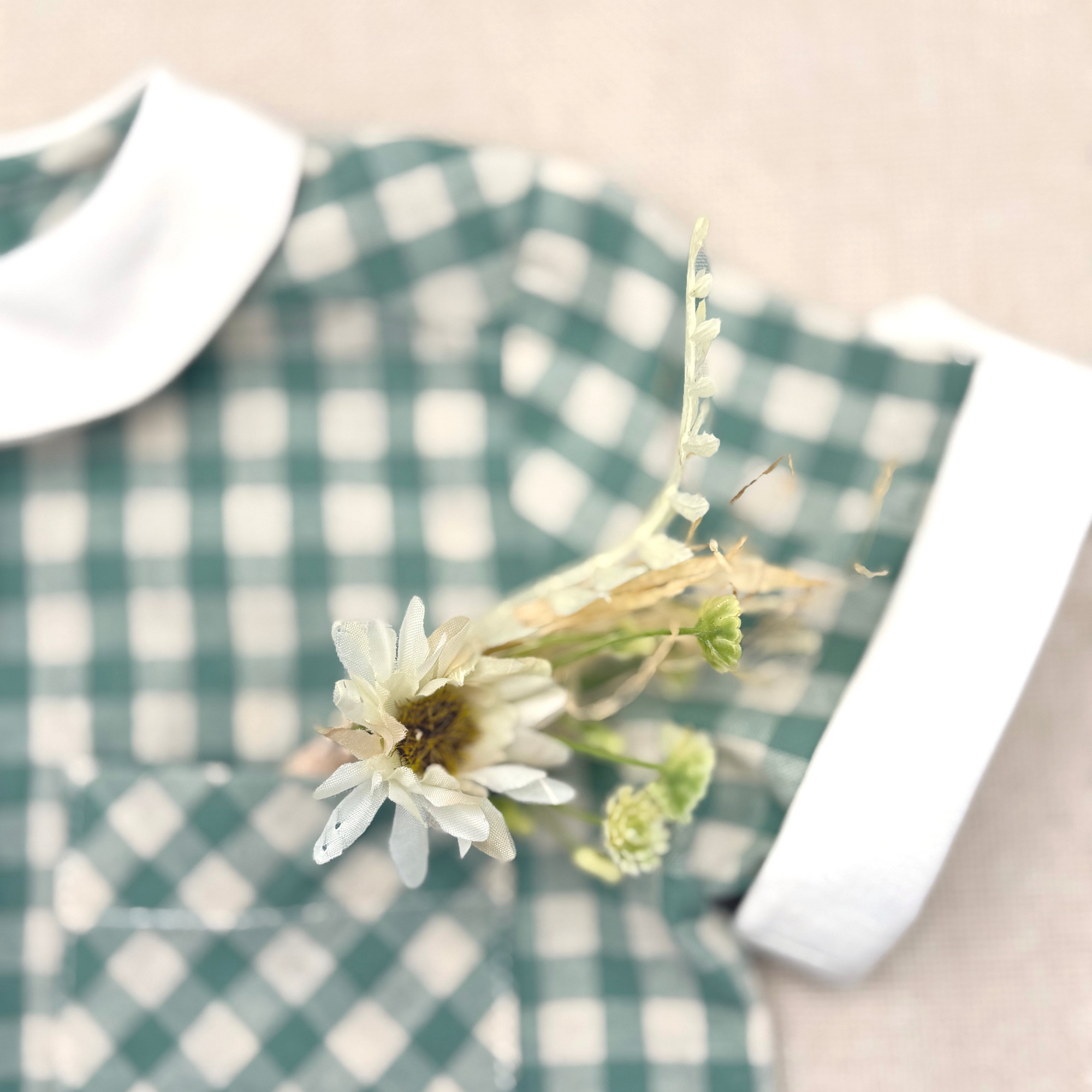 Green and white checkered dress with a white flower on a beige background