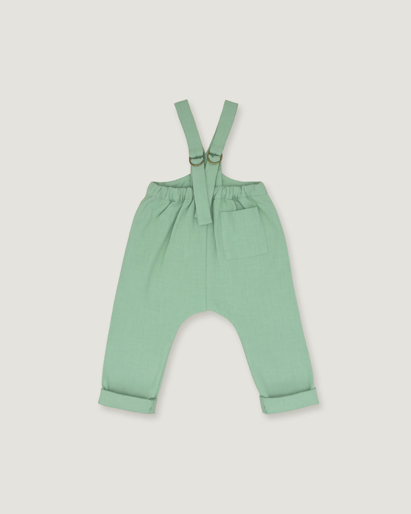 A pair of baby or toddler sage green suspenders with adjustable straps and a front pocket, laid flat on a light gray background.