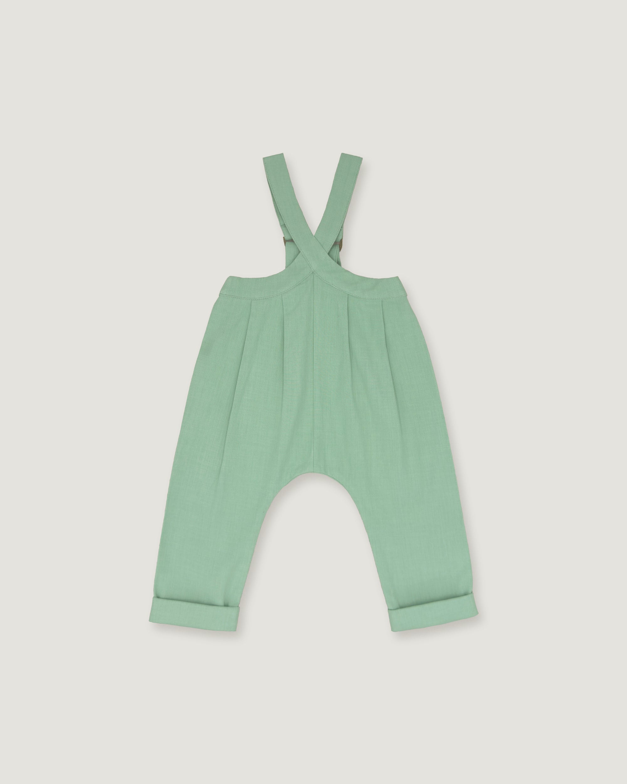 A mint green baby romper with adjustable shoulder straps and a wide leg design, shown flat on a light gray background.