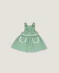 A sage green baby dress with white trim details, featuring a flared skirt and front pockets, shown against a solid light gray background.