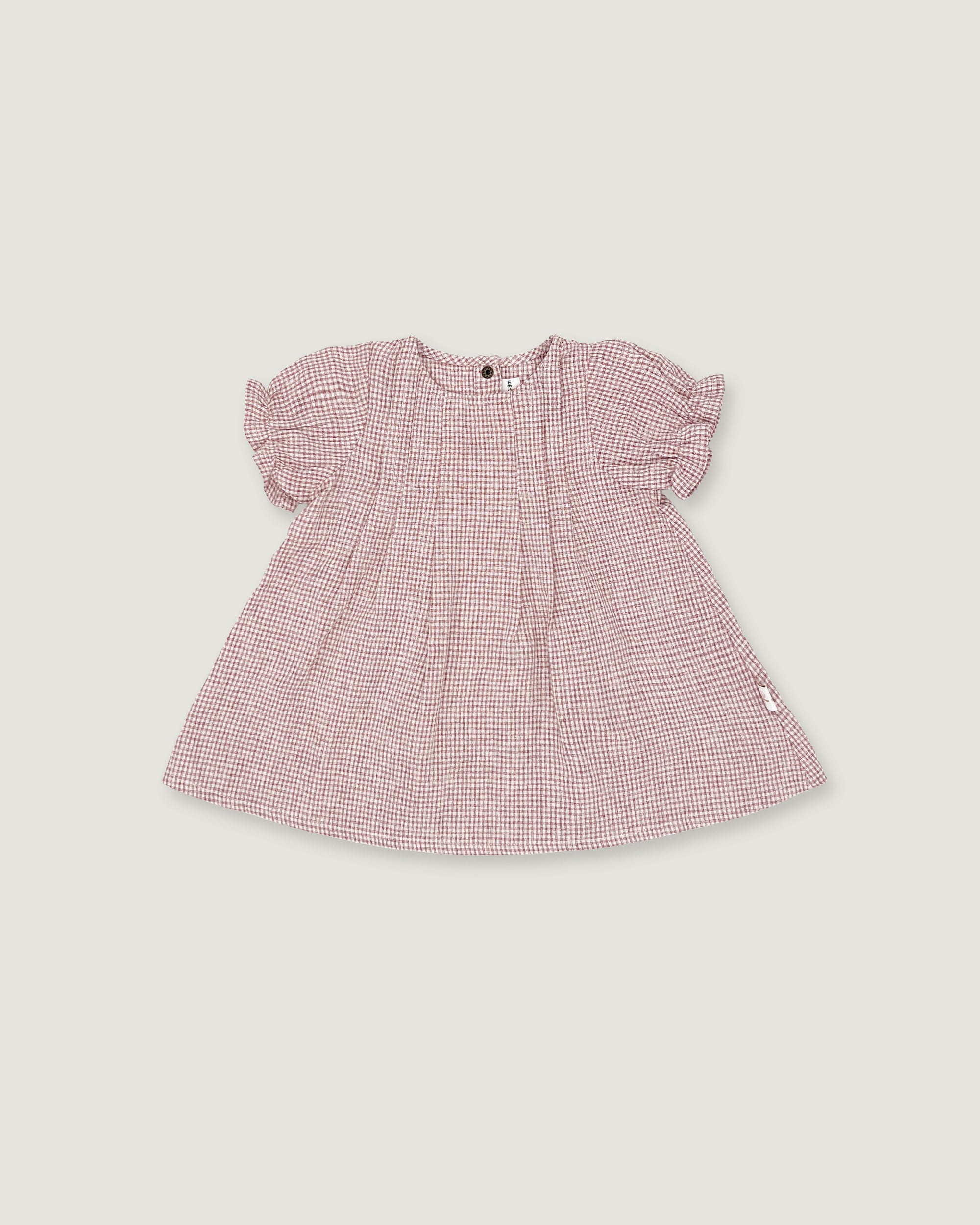 A pink and white micro-check patterned baby dress with short puff sleeves, shown flat on a light gray background.