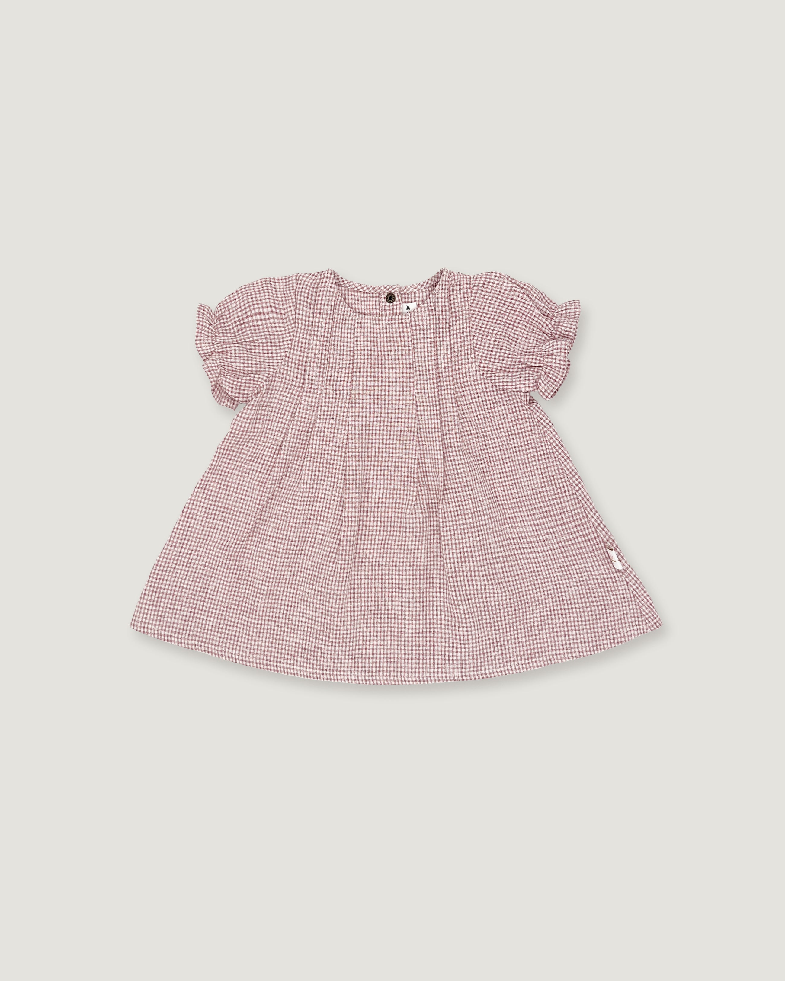 A pink and white micro-check patterned baby dress with short puff sleeves, shown flat on a light gray background.