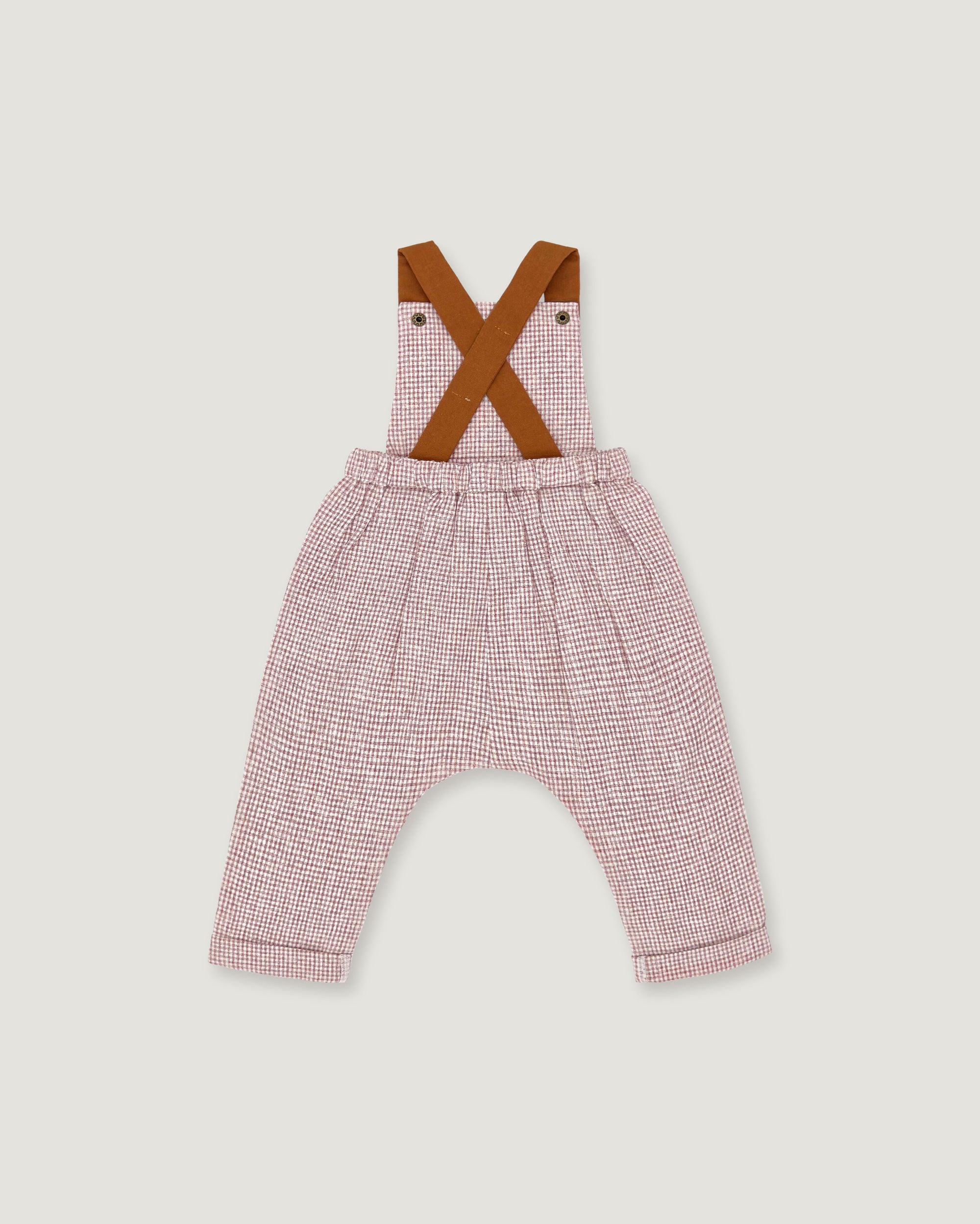 A baby romper with pink and white micro-check patterned pants, brown suspenders, and an elastic waistband, shown flat on a light gray background.